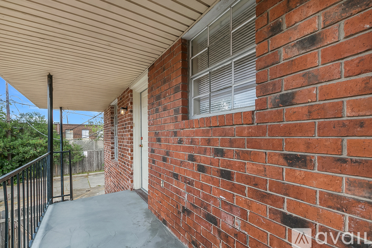A red brick wall with a window and a metal railing.