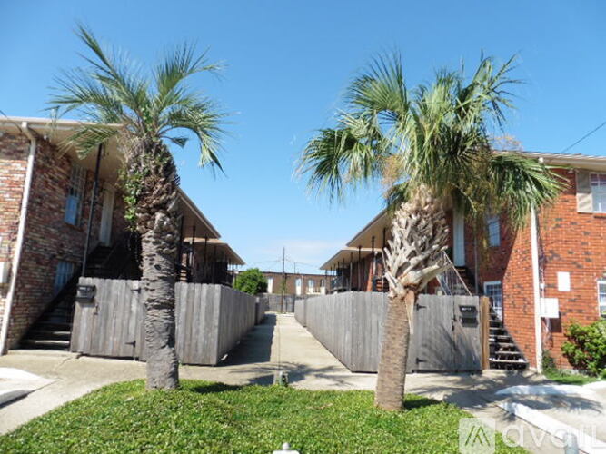 Two palm trees in front of a brick building.