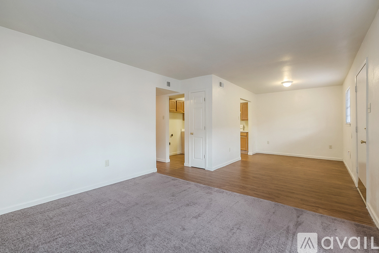 A spacious room with a grey carpet and wooden floors.