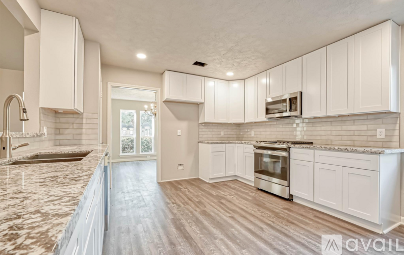 A kitchen with white cabinets and a marble countertop.