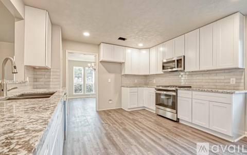 A kitchen with white cabinets and a marble countertop.