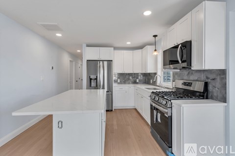 A kitchen with white cabinets and a wooden floor.
