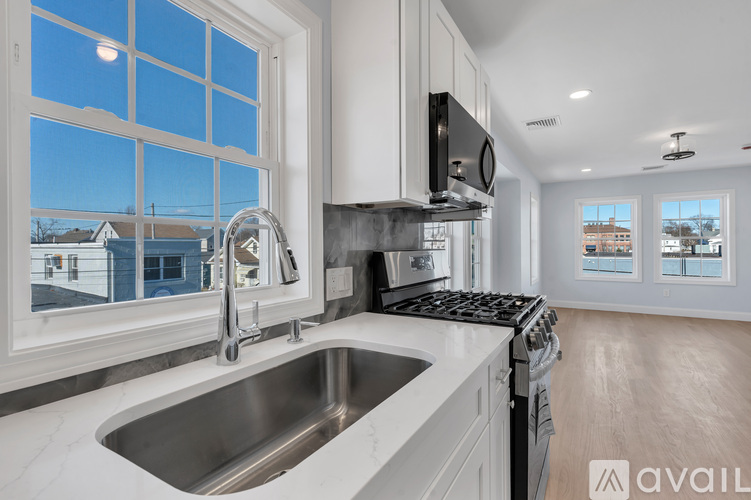 A modern kitchen with a stainless steel sink and a window overlooking a residential area.