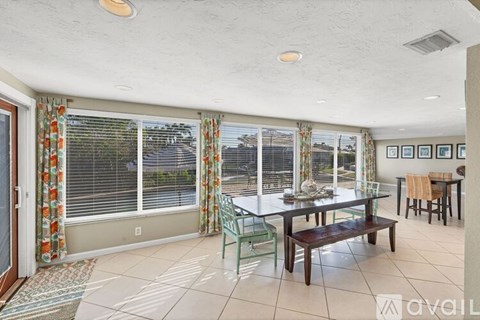 A dining room with a table set for four and a view of the backyard.