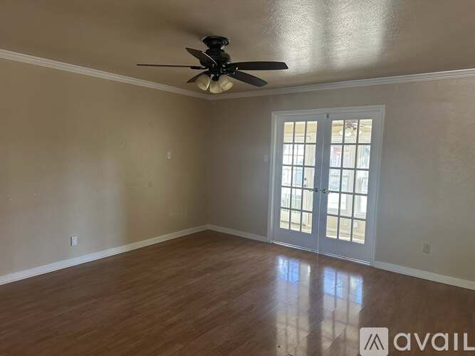 A room with a ceiling fan and a sliding glass door.