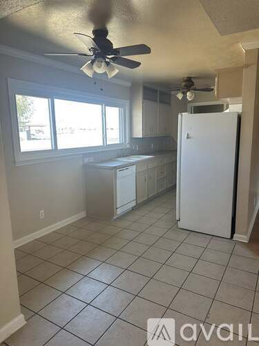 A kitchen with white appliances and a ceiling fan.
