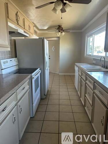 A kitchen with white cabinets and a tile floor.