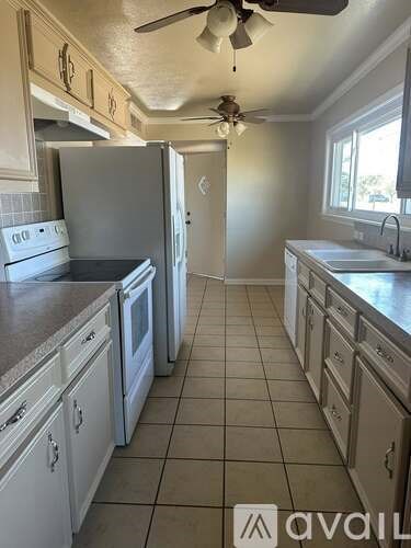 A kitchen with white cabinets and a tile floor.