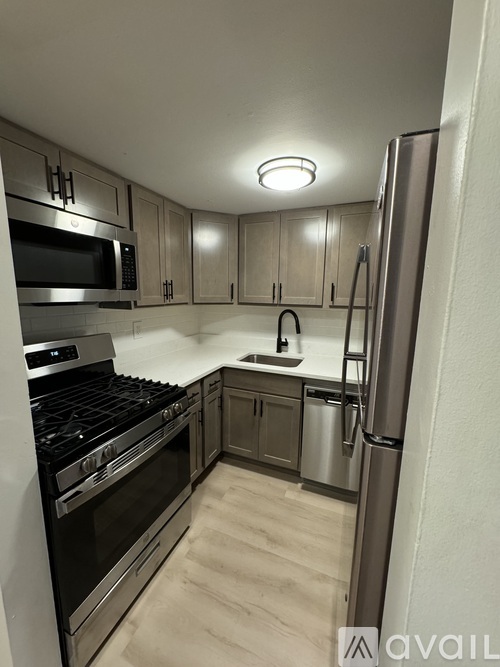 A kitchen with a refrigerator, stove, and microwave.