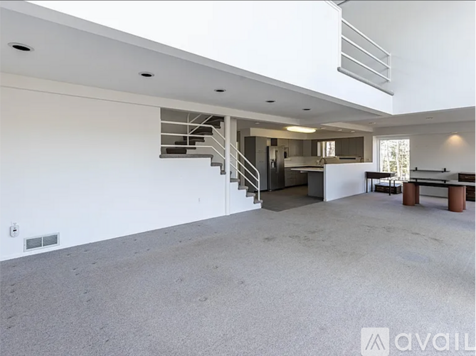 A spacious, empty living room with a staircase leading to the upper level.