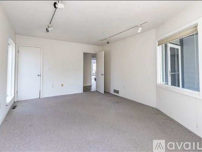 A spacious empty room with white walls and carpeted floor.