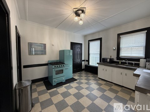 A kitchen with a blue stove and checkered floor.