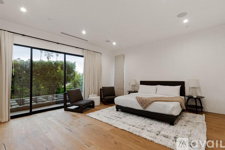 A bedroom with a large bed and a chair by the window.
