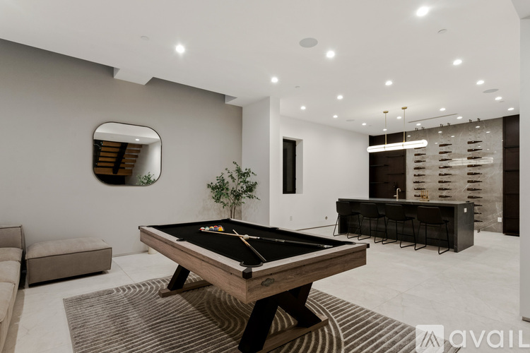 A pool table is in the middle of a room with a mirror on the wall.