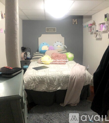 A bedroom with a bed, a laptop, and a few stuffed animals.