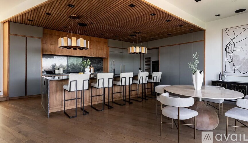 A modern kitchen with a wooden ceiling and a dining table set for four.