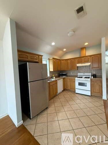 A kitchen with wooden cabinets and a tiled floor.