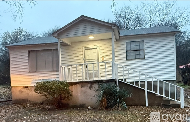 A house with a front porch and a small tree in front.