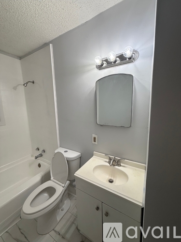 A bathroom with a toilet, sink, and mirror.