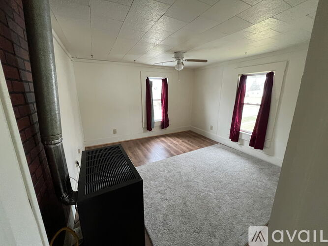 A room with a ceiling fan and a radiator on the floor.
