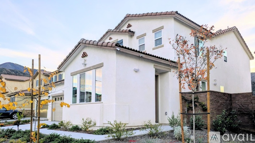 A white house with a brown roof and a sign that says "available" in front of it.