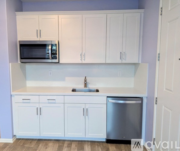 A kitchen with white cabinets and a stainless steel dishwasher.