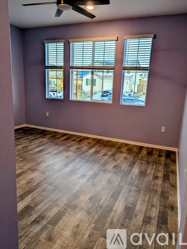 A room with wooden flooring and a window with blinds.