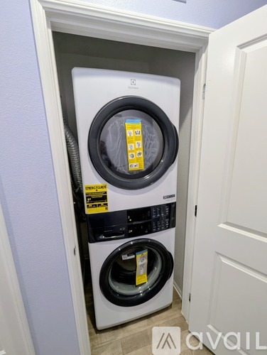 A white dryer is in a small space next to a white door.