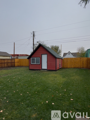 A red shed sits in a grassy backyard.