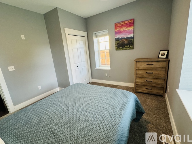 A bedroom with a bed, dresser, and poster.