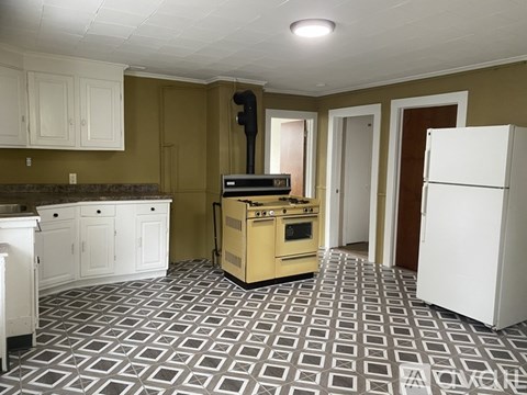 A kitchen with a white fridge and a black vacuum cleaner.