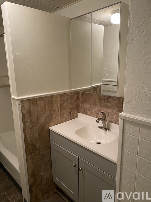 A bathroom with a sink, mirror, and cabinet.