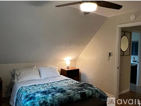 A bedroom with a bed, nightstand, and a ceiling fan.