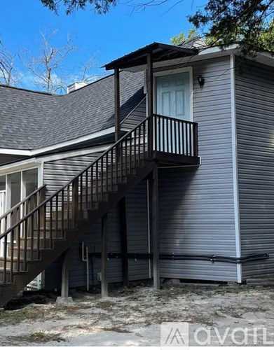 A house with a grey siding and a balcony with a staircase leading to it.