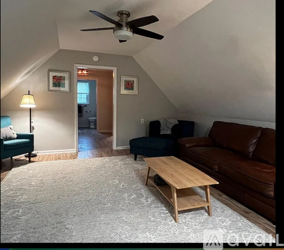 A living room with a brown couch, a wooden coffee table, and a ceiling fan.
