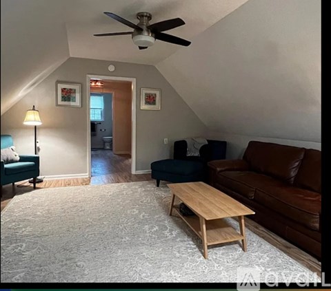 A living room with a brown couch, a wooden coffee table, and a ceiling fan.