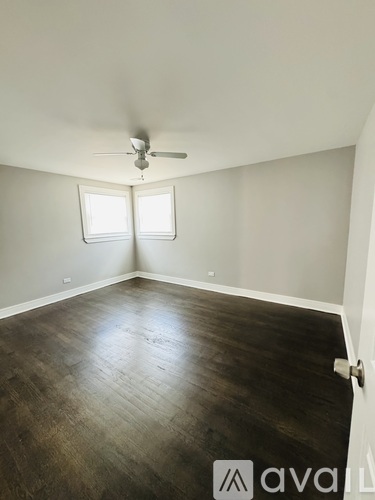 A room with a ceiling fan and two windows.