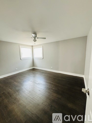 A room with a ceiling fan and two windows.