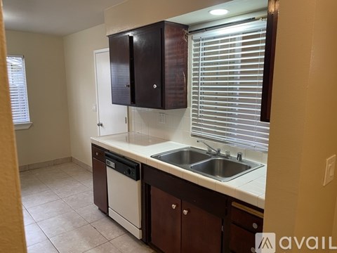 A kitchen with brown cabinets and a white dishwasher.