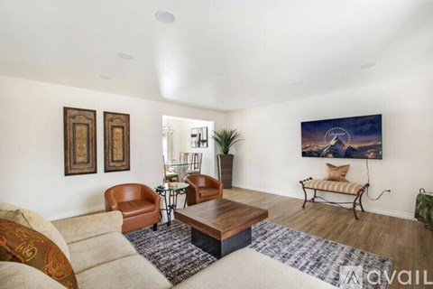 A living room with a brown leather chair, a wooden coffee table, and a painting on the wall.