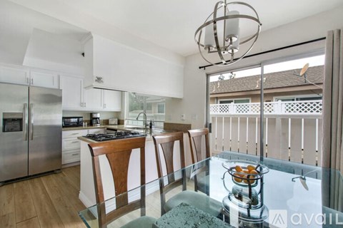 A modern kitchen with a glass table and stainless steel appliances.