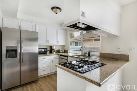 A kitchen with a stainless steel refrigerator and a granite countertop.