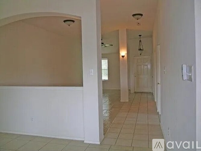 A long hallway with a light on the ceiling and a door at the end.