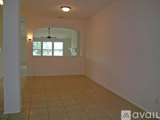 A spacious room with tiled flooring and a ceiling fan.