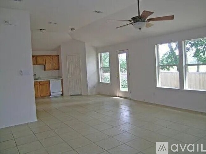A spacious living room with a ceiling fan and large windows.