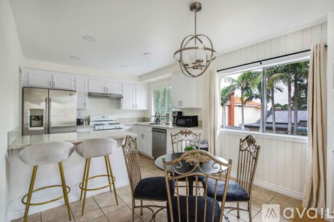 A kitchen with a table and chairs in front of a window.
