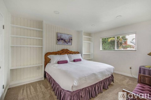 A bedroom with a large bed and a window showing a view of trees.