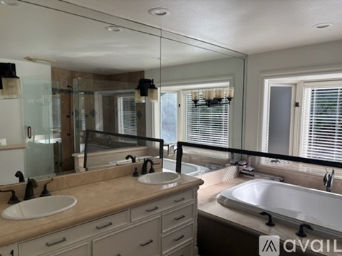 A bathroom with a large mirror, two sinks, and a bathtub.