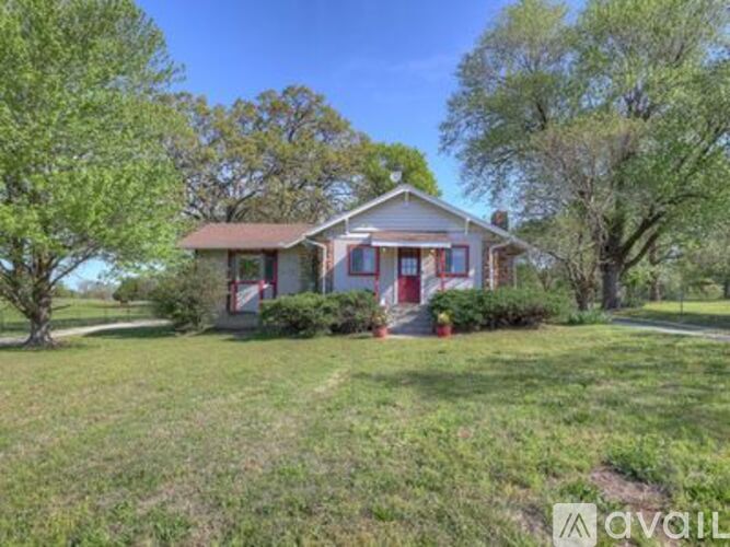 A house with a red door is surrounded by greenery.