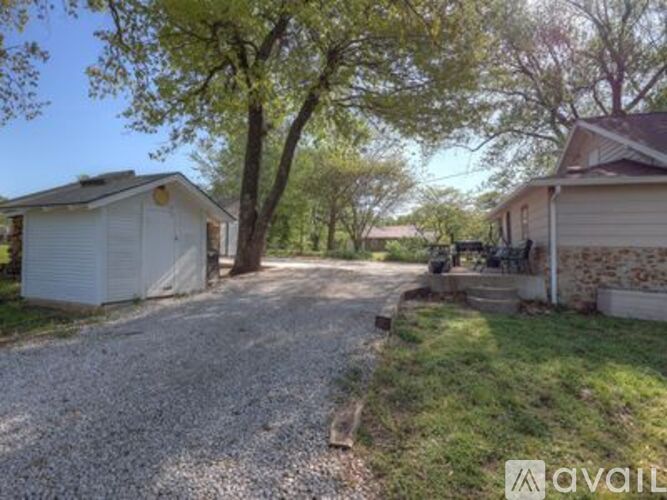 A gravel driveway leads to a white garage and a house with a brown roof.